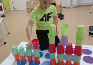 Konrad układa wieże z kolorowych kubeczków